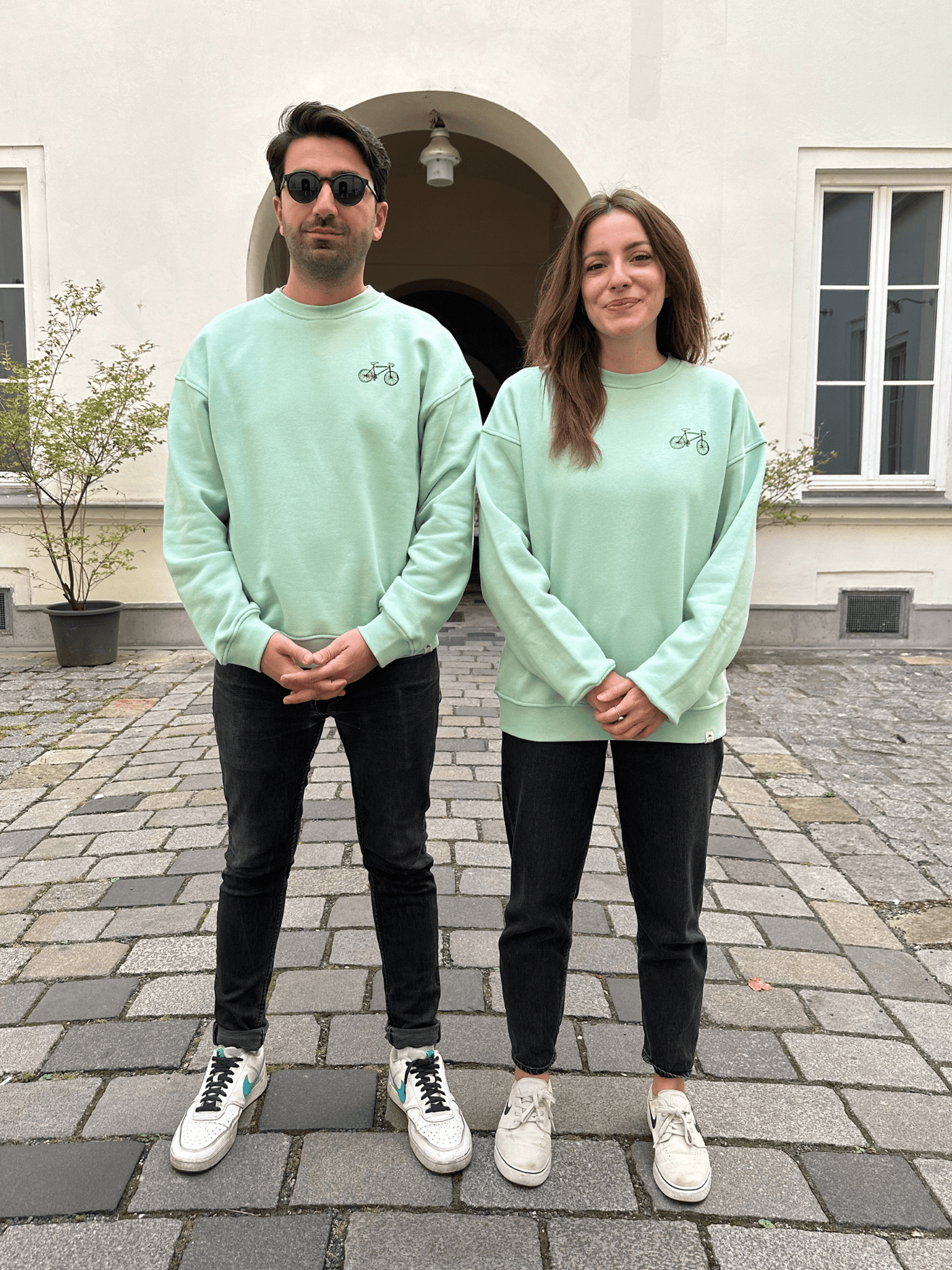 Menschen in fairem Sweateshirt in Türkis mit Fahrrad-Motiv aus Wien von vorne